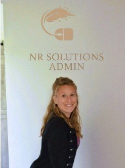 Roxane Nos - Portrait professionnel devant logo NR Solutions Admin